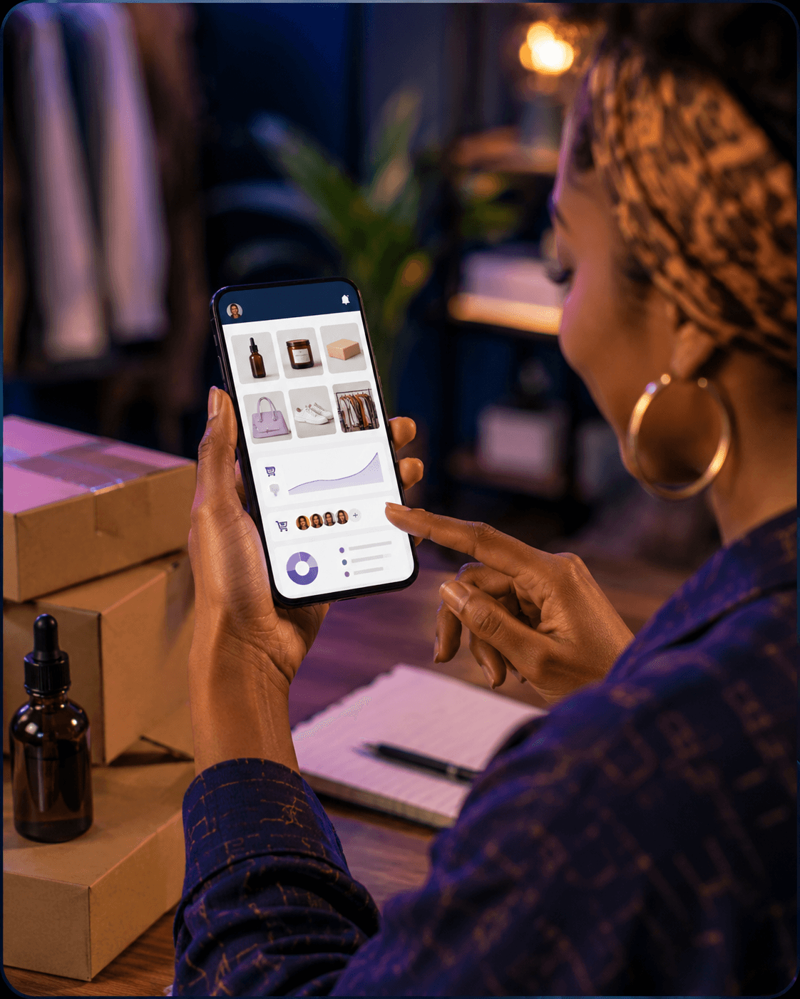 A woman manages her e-commerce business dashboard on a smartphone, surrounded by shipping packages.